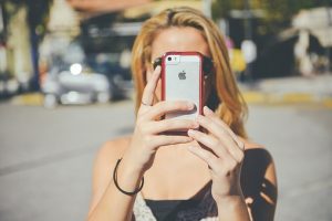 blond woman holding a phone taking a photo